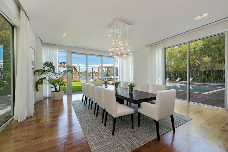 In this contemporary dining room, an elegant chandelier hangs above a large dining table with room for 12 people. #DiningRoom