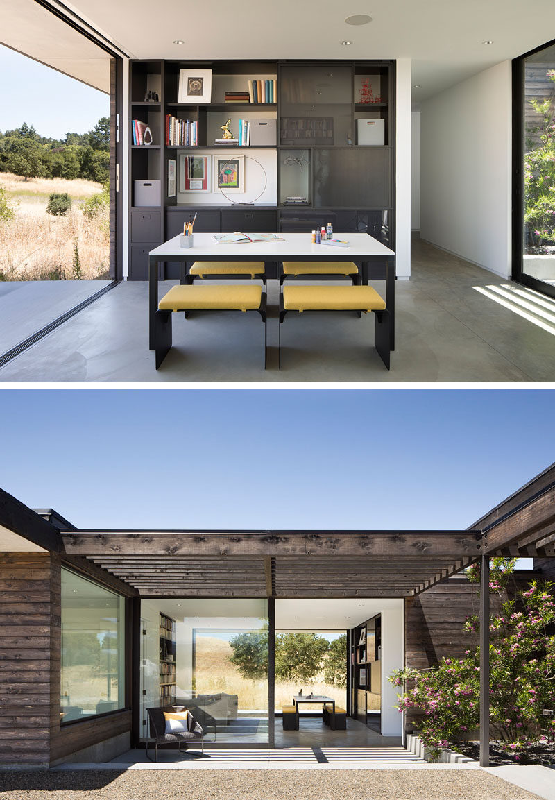 This modern house has a home office with built-in shelving, a communal work table, and a lounge area. Large sliding glass doors open the interiors to the outdoor spaces. #ModernHomeOffice #HomeOffice #ModernHouse