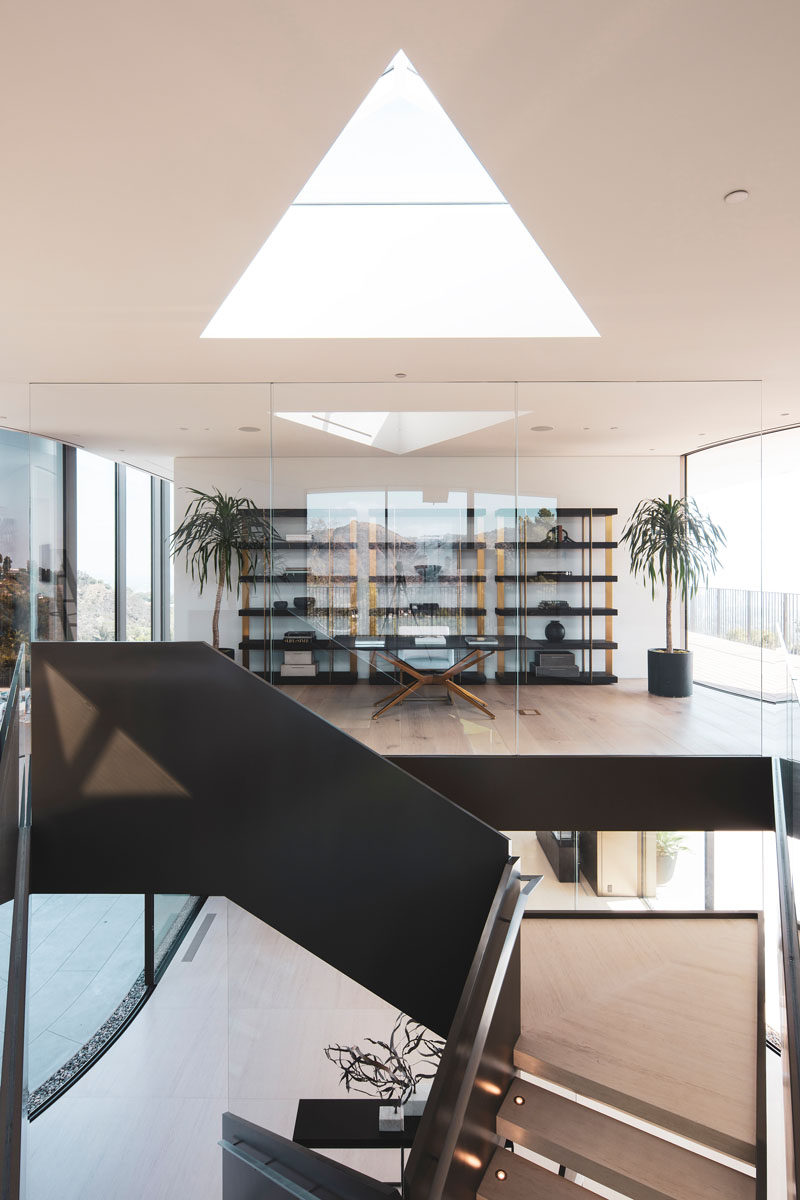 This modern house has a glass enclosed home office that uses shelving as a backdrop for the desk. #HomeOffice #InteriorDesign