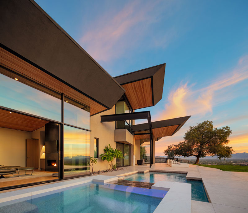 This modern house is open to a landscaped yard that has three sections. A swimming pool and spa, an outdoor kitchen, and a lounge area with a fire pit. #Landscaping #SwimmingPool #ModernHouse