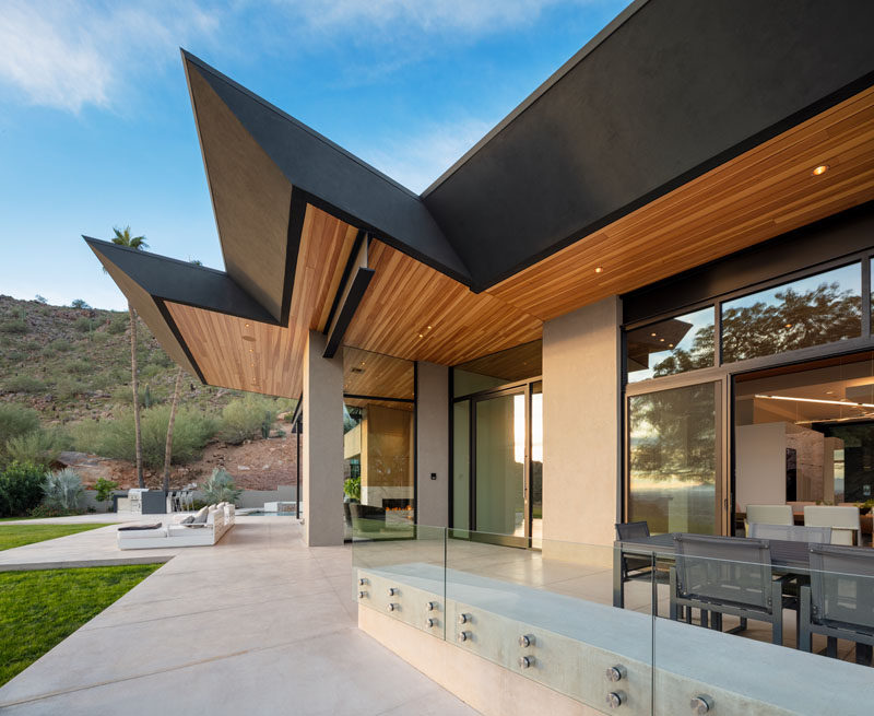 This modern house has a large patio with outdoor dining, a lounge area with a fire pit, and a swimming pool. #Patio #Architecture