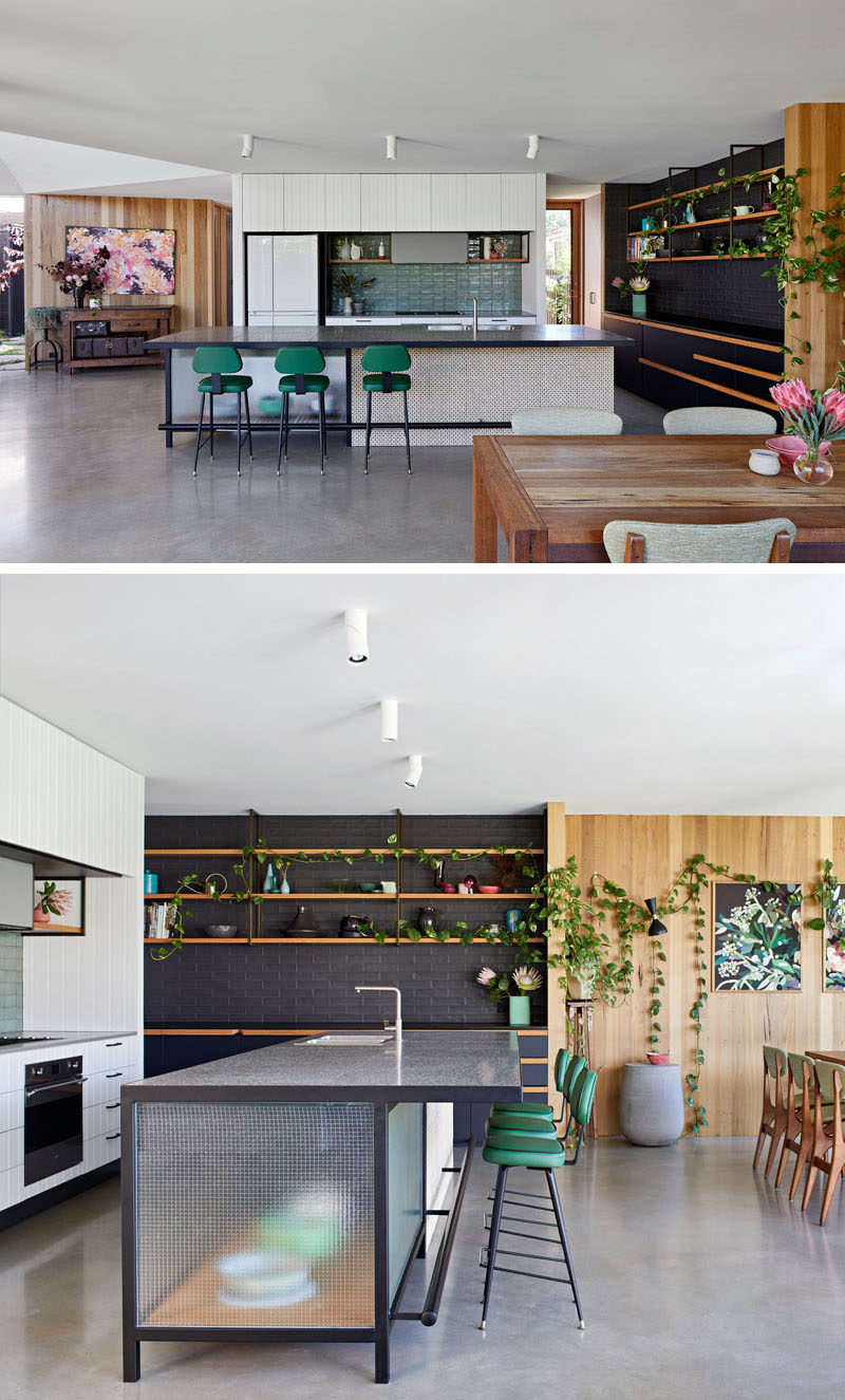 This modern kitchen has a combination of light and dark cabinetry with natural elements, while a large island provides extra storage and space for seating. #KitchenDesign #ModernKitchen