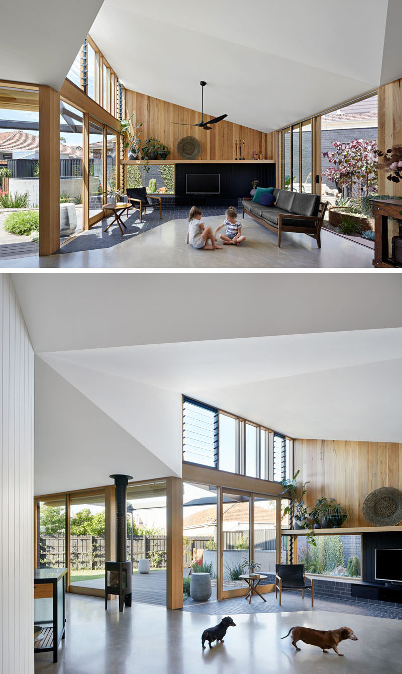 Inside this modern house extension, the high ceilings create a lofty and open feeling for the living room, while the windows flood the space with natural light. The dark brick from the patio outside continues to flow into the living room to meet the concrete floor. #LivingRoom #HouseExtension