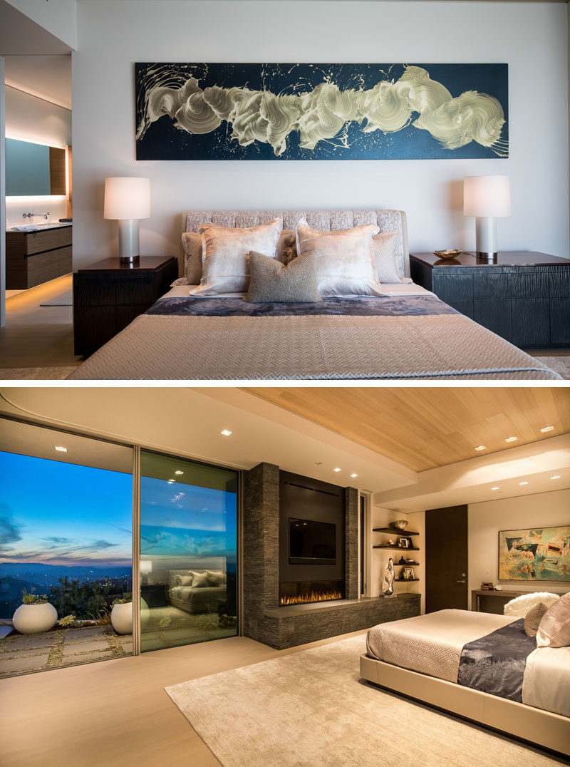 In this modern master suite, there's a painting above the bed by James Nares, and opposite the bed is a fireplace, that sits beside sliding glass doors that open to the back patio. #MasterBedroom #Fireplace #BedroomDesign