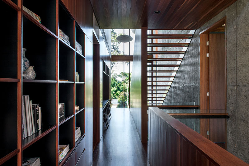 Rich wood cabinetry, open shelving, and a built-in desk, feature the hallway of this modern house. #Shelving #Cabinetry