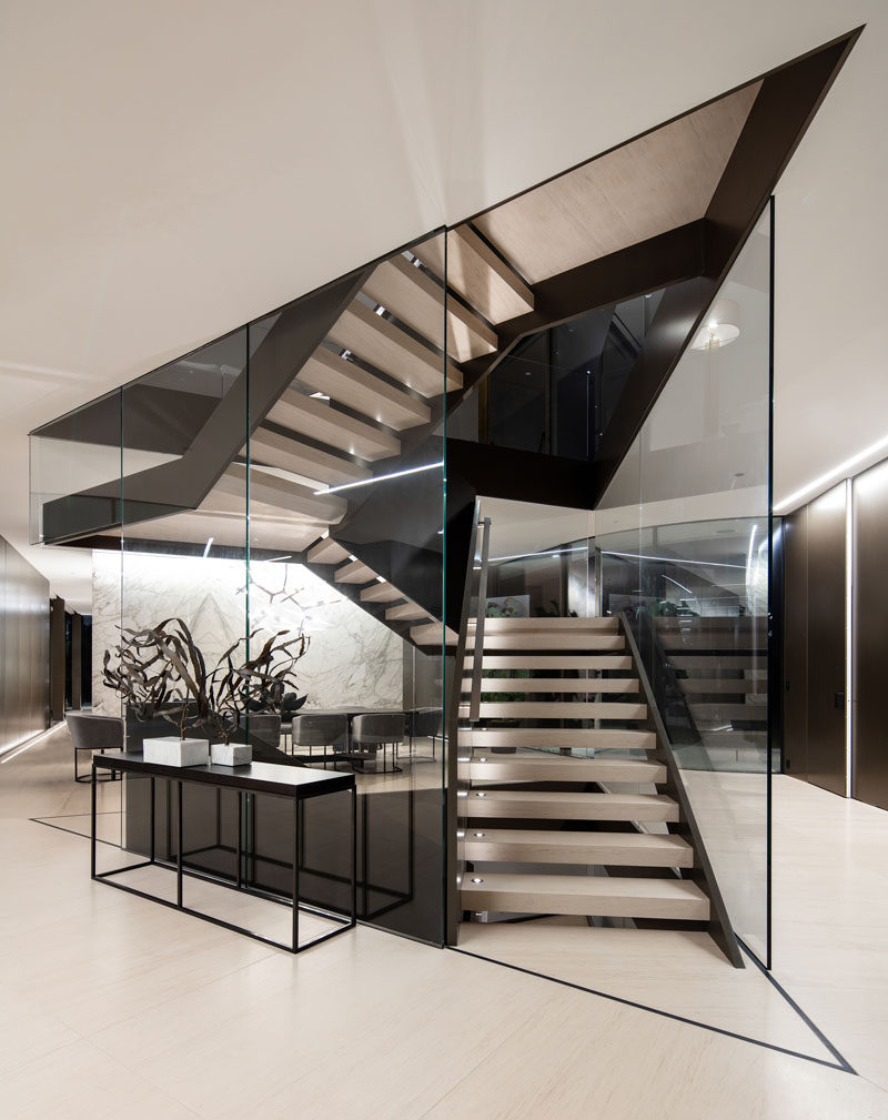 A large and sculpture staircase made of metal and glass is central to this modern house. #Staircase #ModernStairs