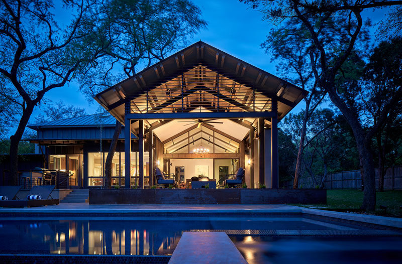 This modern house has an outdoor living space that leads down to a negative-edge pool with views into the woods. #ModernHouse #SwimmingPool