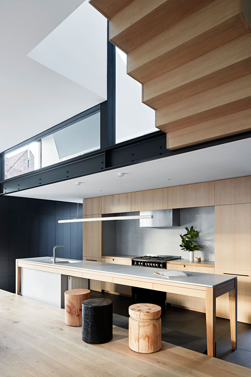 In this modern kitchen, a long island provides ample food prep area, while minimalist wood cabinetry lines the wall. #KitchenDesign #ModernKitchen