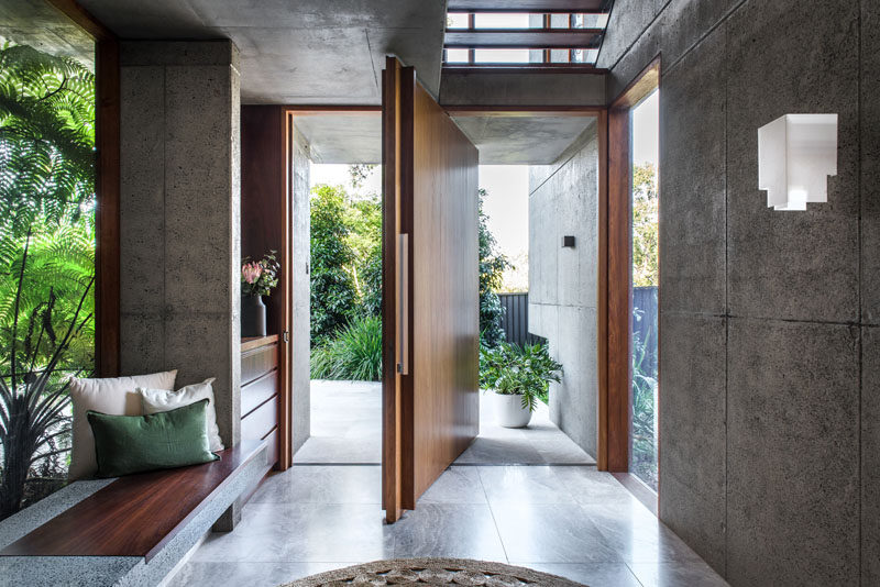 A large pivoting wood front door welcomes visitors to this modern house. #FrontDoor #PivotingDoor #WoodDoor