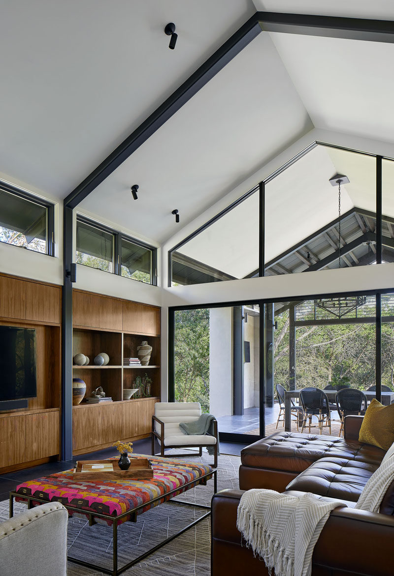 A light-filled living room with high ceilings and built-in cabinetry was added to the back of this modern house. #ModernLivingRoom #LivingRoom #HighCeiling