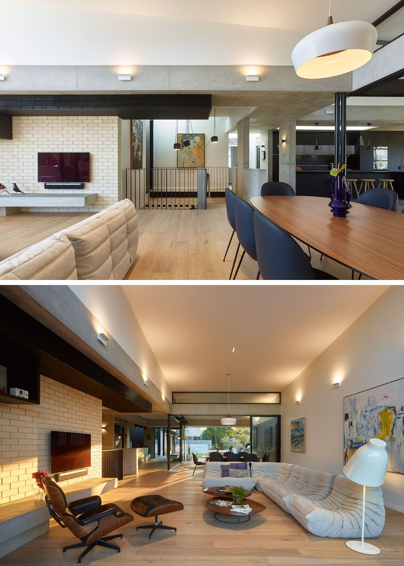 In this modern house, a single pendant light hangs above the wood dining table to anchor it in the open plan interior, while the living room is focused on the television and the street view at the front of the house. #LivingRoom #DiningRoom #OpenPlanInterior