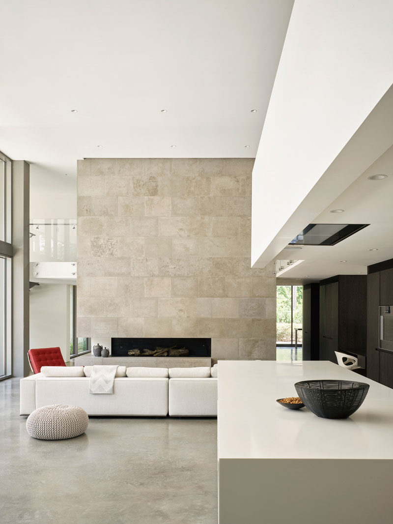 This modern house features high ceilings, and a large limestone wall that surrounds a fireplace in the living room. #HighCeilings #LivingRoom #LimestoneWall