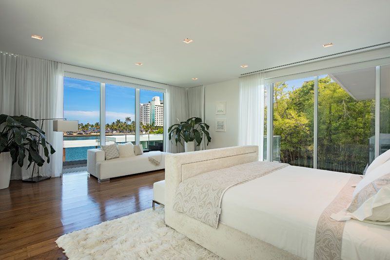 Floor-to-ceiling windows provide water and palm tree views for this modern master bedroom. #MasterBedroom #BedroomDesign #Windows