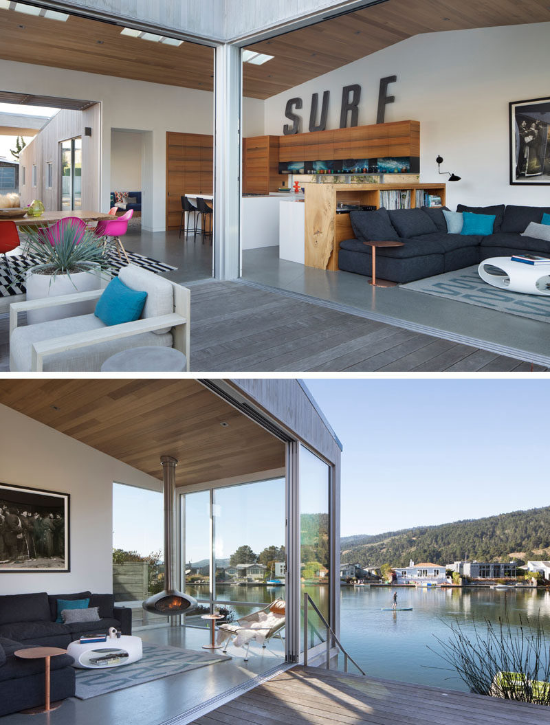 The main social areas of this modern house are all open plan, with a wood shelving unit separating the living room from the dining room. Large sliding glass doors open to create an indoor/outdoor living environment. #InteriorDesign #ModernHouse