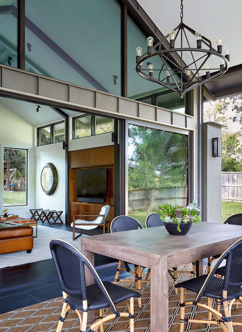 The living room of this modern house opens to a new covered outdoor living space, that's been furnished with an alfresco dining area. #OutdoorDining #ModernHouse