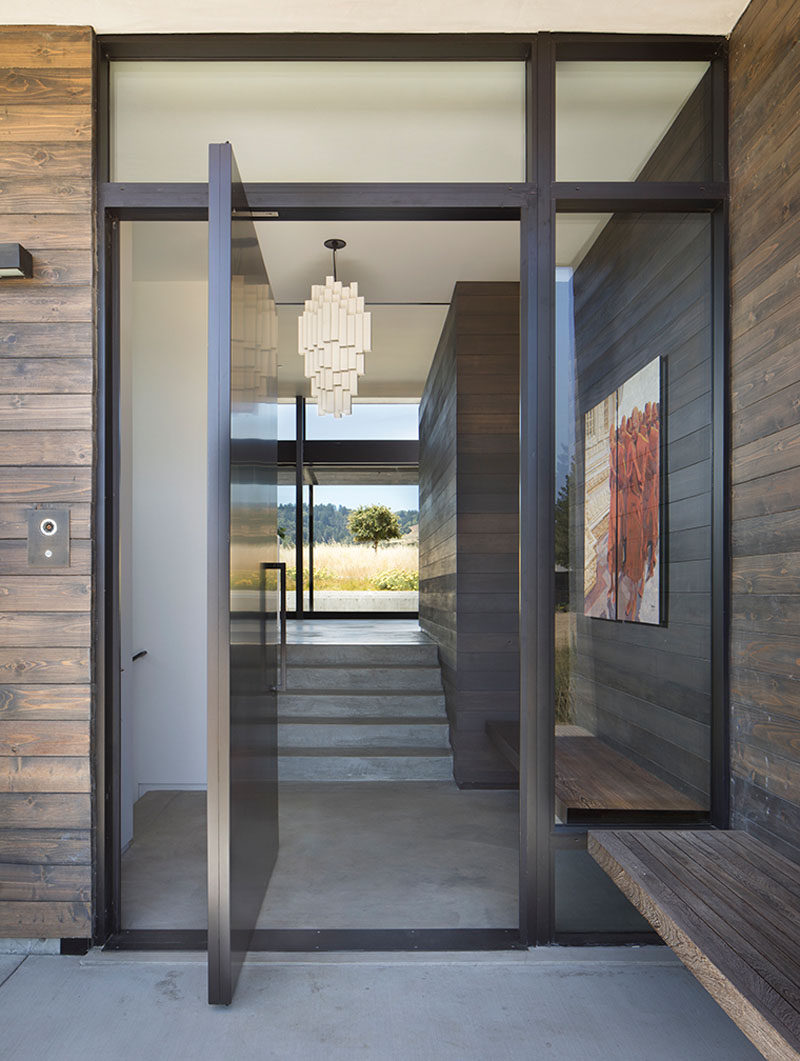 Welcoming visitors to this modern house is a large pivoting front door that opens up to the social areas of the home. #PivotingFrontDoor #FrontDoor