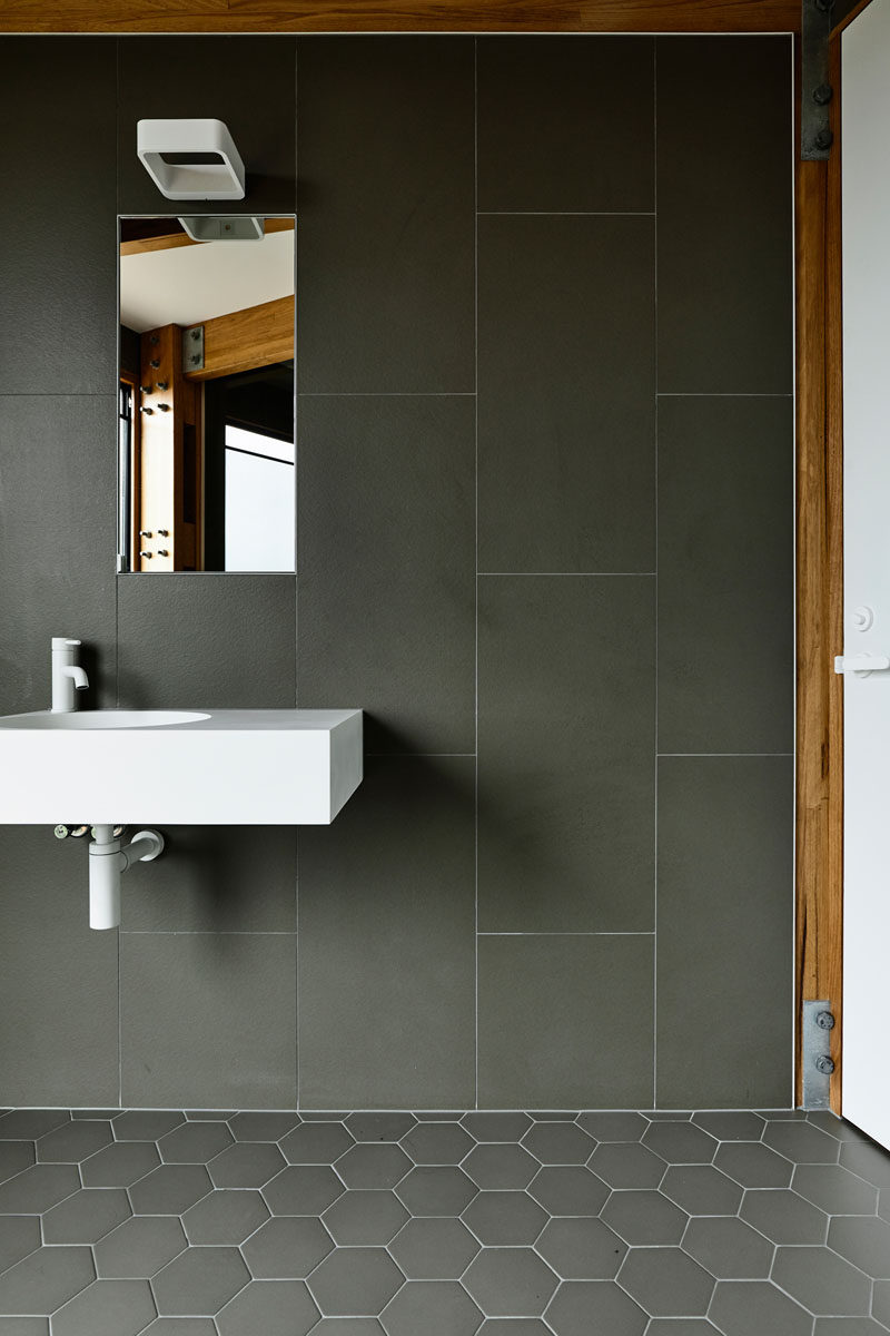 In the bathroom, large format tiles cover the walls, while smaller hexagonal tiles cover the floor. #Tiles #GreyTiles #Bathroom