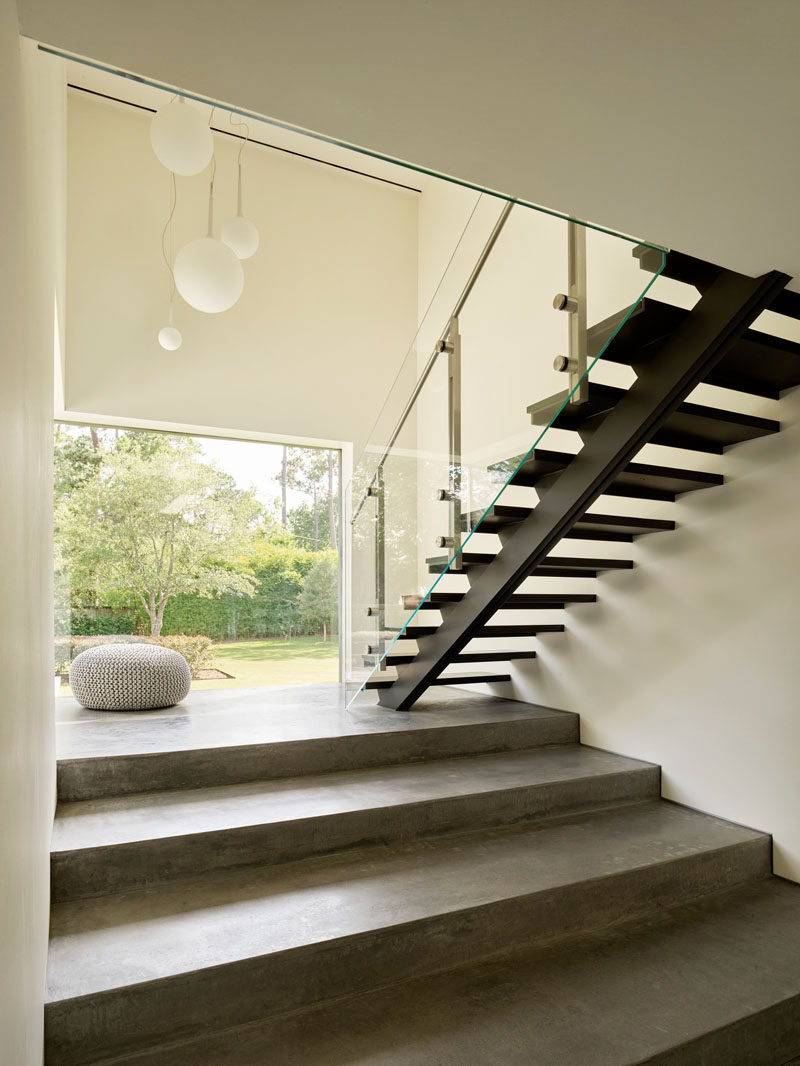 This modern staircase provides a contrast in materials, commencing from the ground plane as three broad concrete amphitheater steps, then transforming into black steel treads and glass as it ascends further. #ModernStairs #Staircase