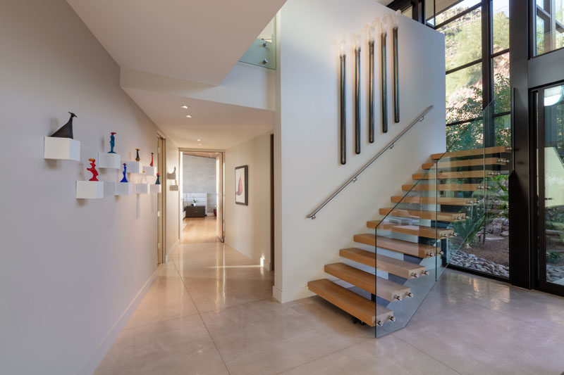 This modern house has wood and steel stairs with a glass handrail, that lead up to the second floor of the home. #ModernStairs #StairDesign