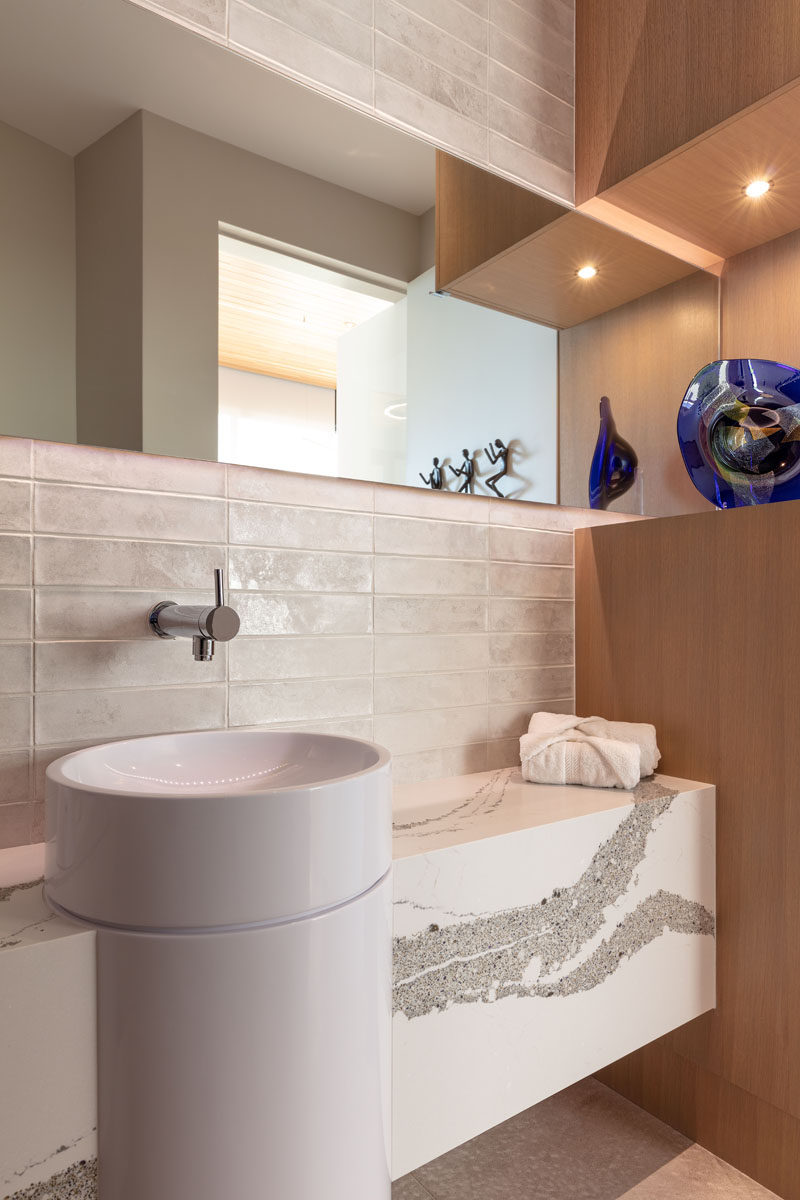 This modern guest bathroom combines wood with white tile and a stone vanity for a contemporary appearance. #GuestBathroom #ModernBathroom #BathroomDesign