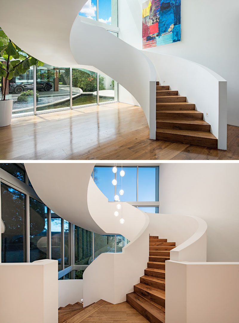 A grand spiral staircase with wood treads, leads to the upper floors of this modern house. #Stairs #SpiralStairs