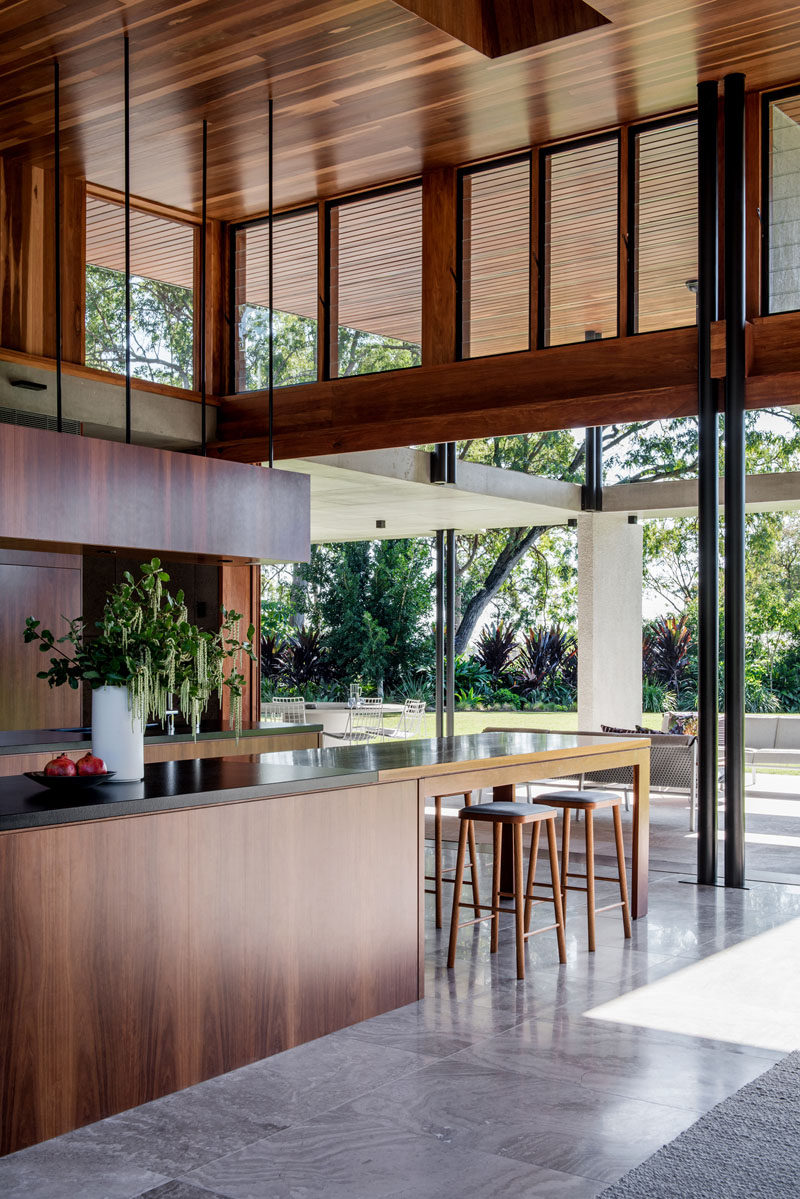 Sliding glass walls open the interior of this modern house to the backyard, creating an indoor/outdoor living environment. #WoodKitchen #InteriorDesign #KitchenDesign