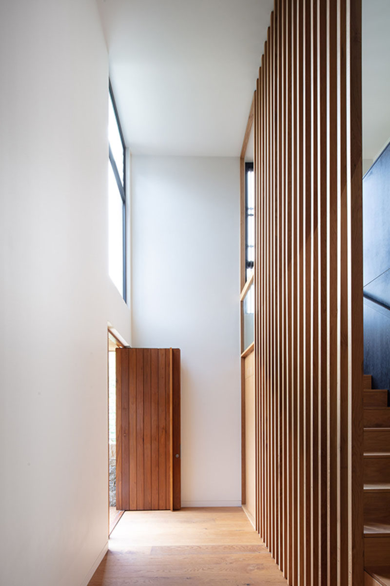 The wood front door opens up to a double height entryway that guides guests to the hallway leading to the social areas of this modern house. #WoodFrontDoor #FrontDoor