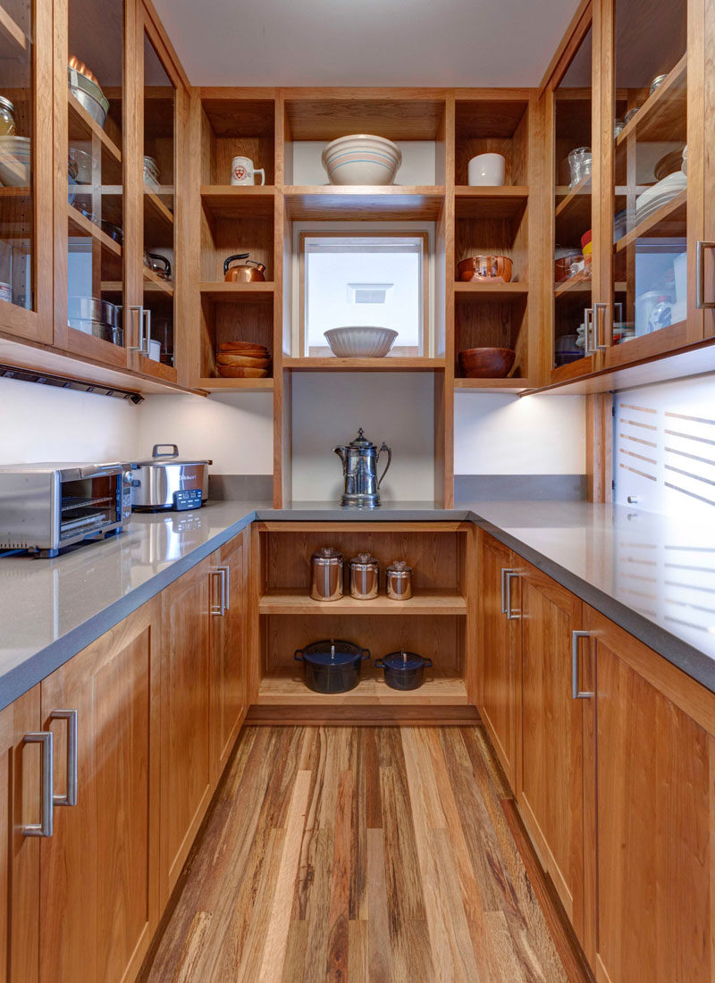 This butler’s pantry allows for an abundance of storage in the form of open shelving, glass-fronted cabinets, and lower wood cabinets. #Pantry #ButlersPantry #KitchenStorage