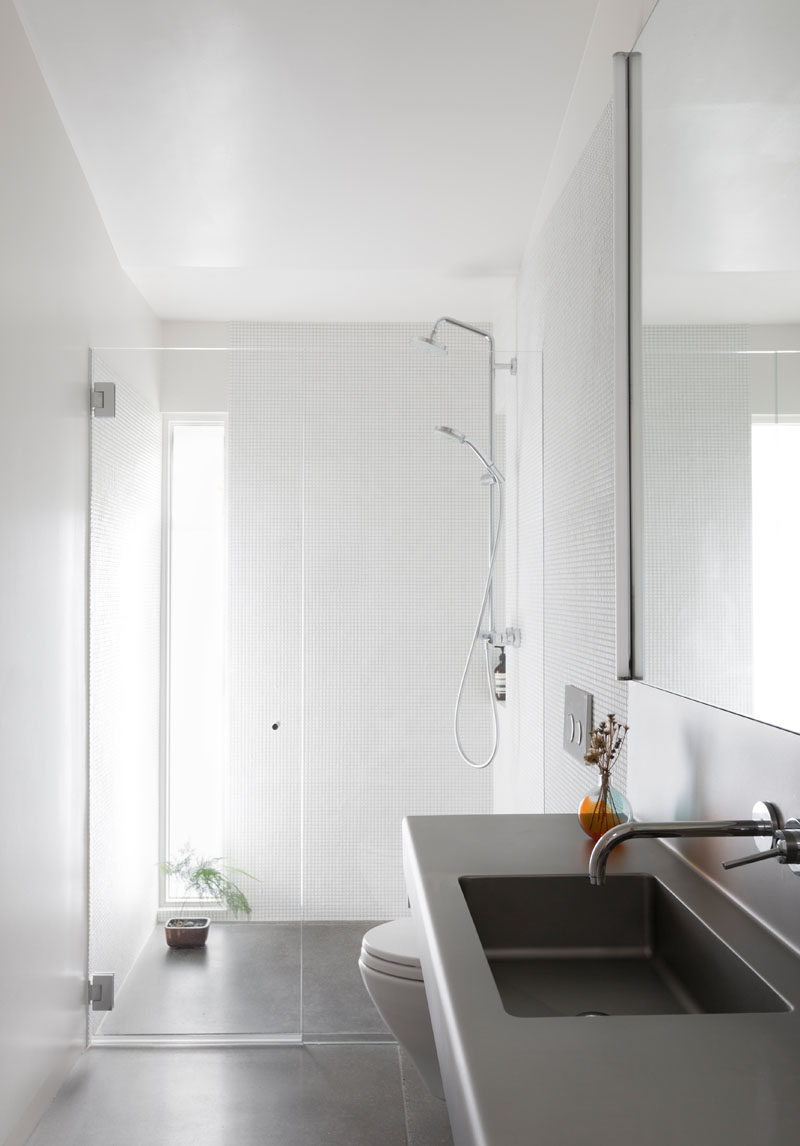 This bathroom received a fresh and modern update, with bright white walls and a window in the shower, adding extra light to the room. #ModernBathroom #BathroomDesign