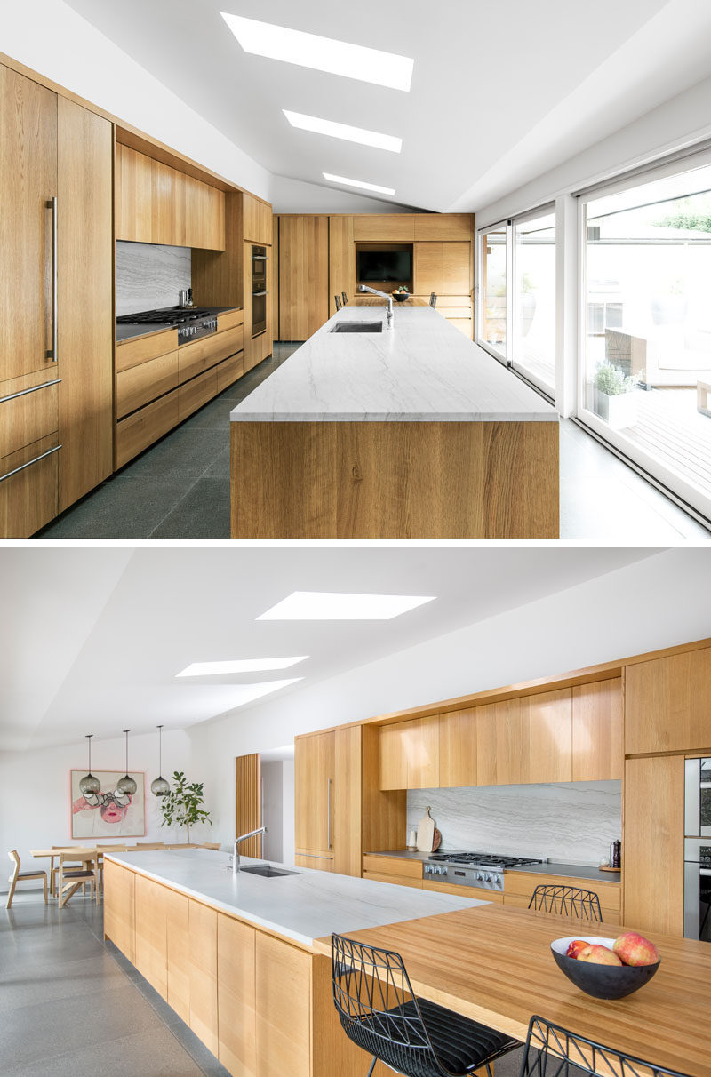 SHED transformed and updated the kitchen in an old ranch house and inserted an oversized kitchen island that takes a commanding position in the space, while providing ample room to cook, eat, and socialize. #ModernKitchen #LargeKitchenIsland #WoodKitchenCabinets