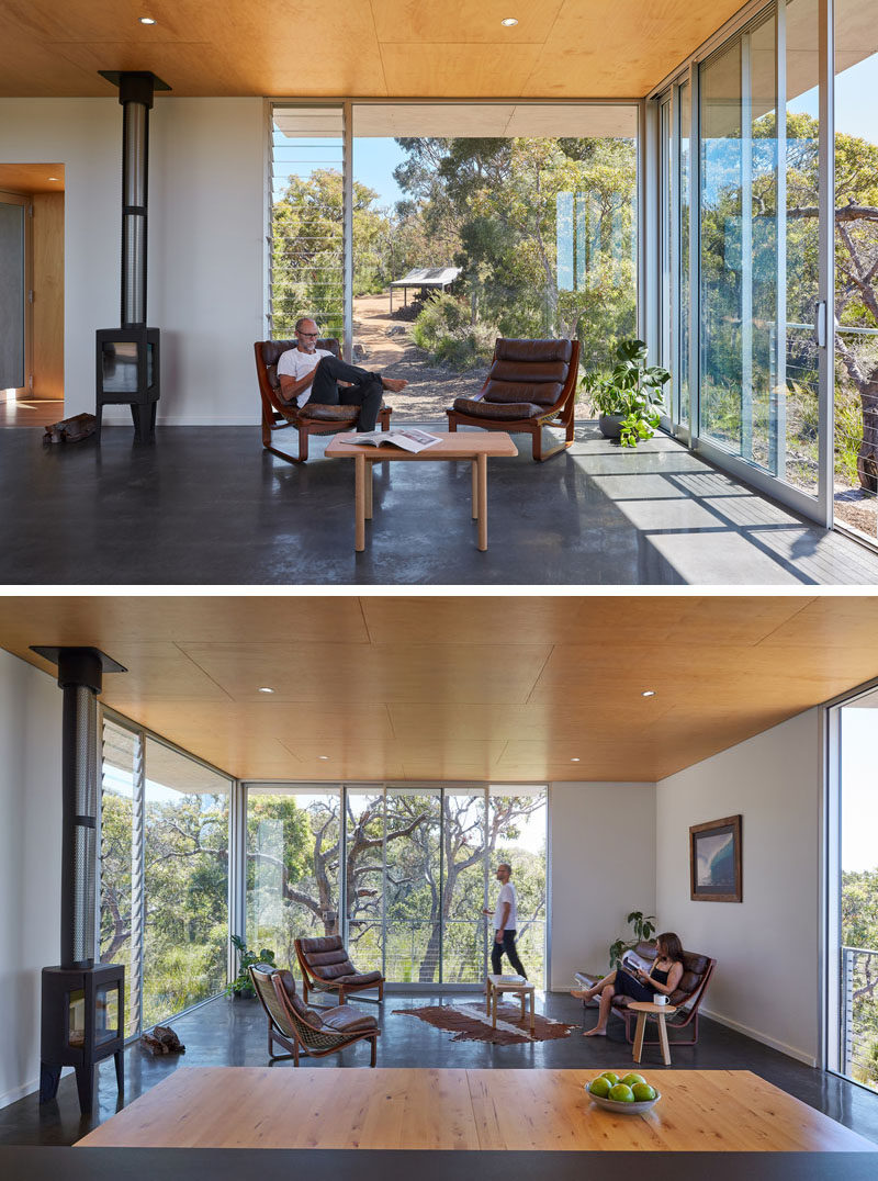 Inside the main floor of this modern house, pine plywood sheets cover the ceiling, while large areas of glass can be slid open to evoke the feeling of being on an open platform up amongst the treetops. #WoodCeiling #LargeWindows #LivingRoom