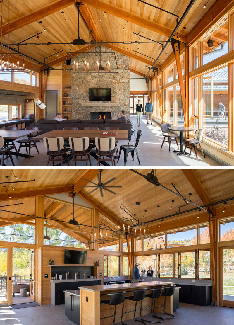 Created to be the vibrant heart of the community at this Colorado ranch, the interior of the activity center features plenty of seating, including a lounge area, games tables, and window seats, as well as a stone fireplace and a bar. #StoneFireplace #Architecture #Bar