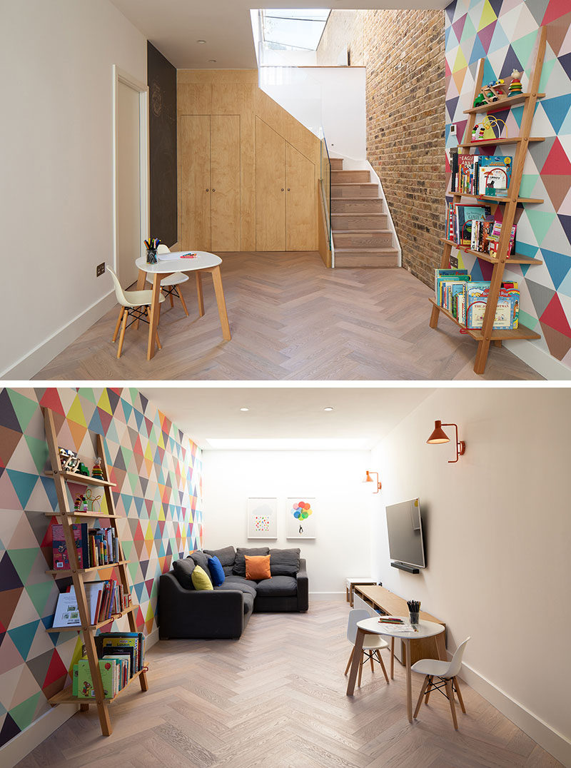 In this modern basement, a brightly colored wall creates a sense of fun, while additional storage has been hidden under the stairs. #ModernBasement #InteriorDesign #Playroom