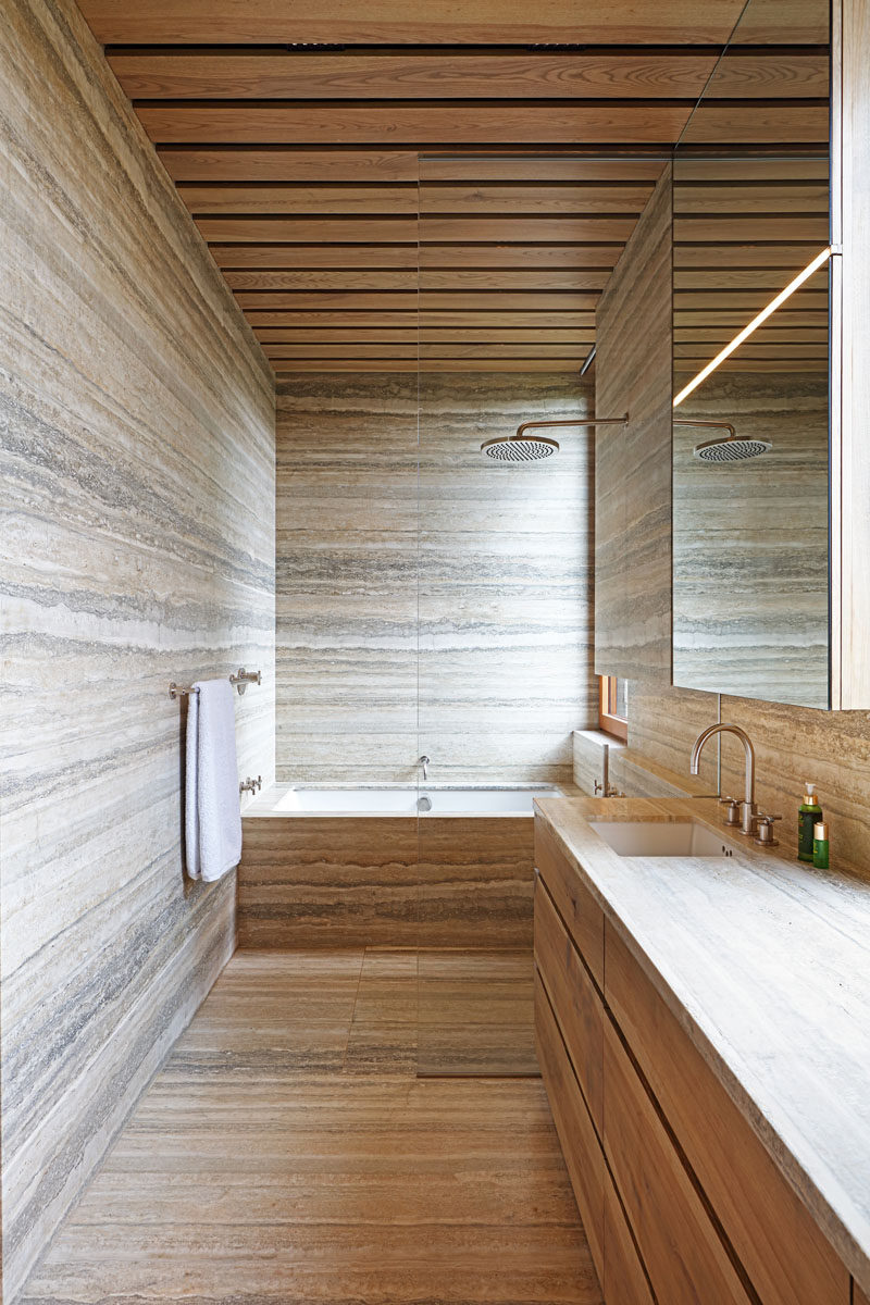 In this modern bathroom, stone covers the floors and walls, while wood has been used for the ceiling and vanity. #BathroomDesign