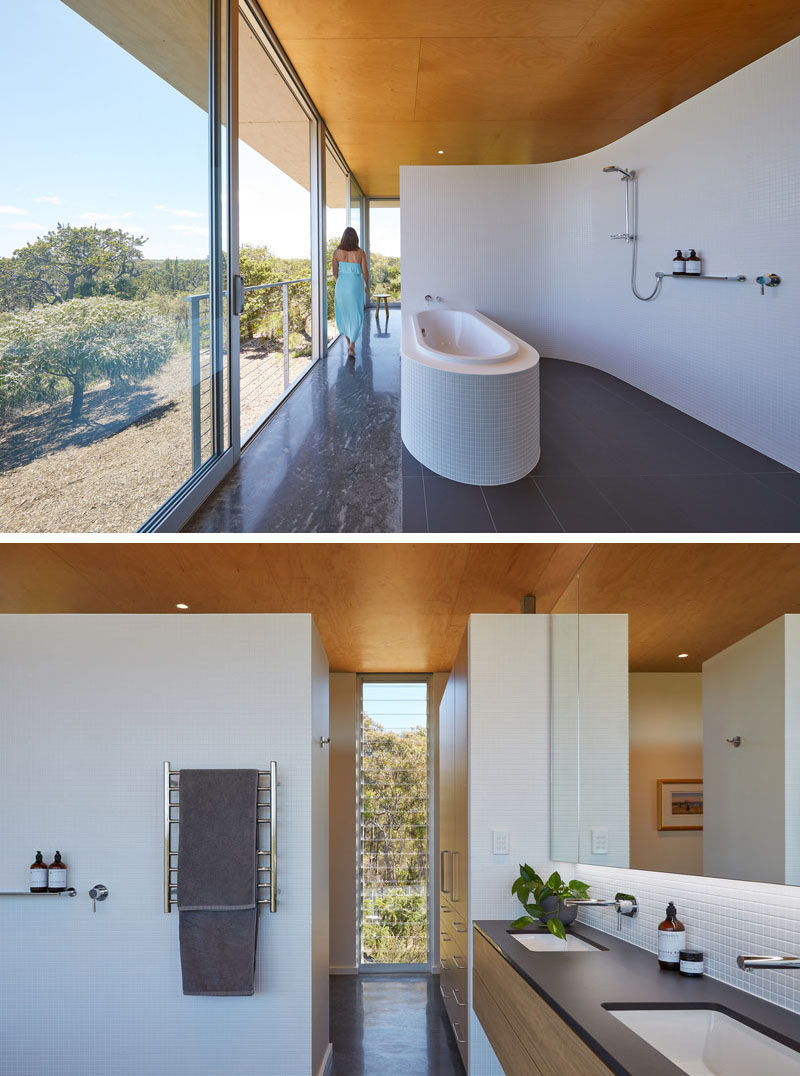 This modern bathroom opens directly onto north facing sliding doors, allowing the home owners to bathe in winter sunshine, while a curved, white mosaic tiled wall acts to softly define this open room and is mirrored in the curved surround to the bath. #ModernBathroom #BathroomDesign