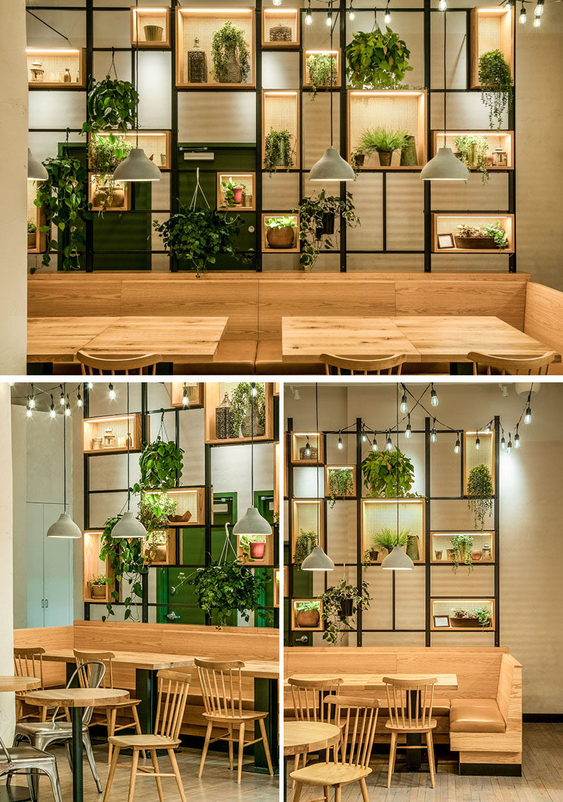 This modern restaurant features wood and leather banquette seating in Garret Glazed bourbon, that's juxtaposed by a wall of live plants hanging in woven cane and wood boxes. #RestaurantDesign #ModernRestaurant #BanquetteSeating #Shelving