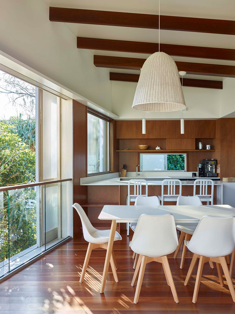 This open plan dining area features a white dining table that complements the white kitchen countertops. #InteriorDesign #DiningRoom #Kitchen