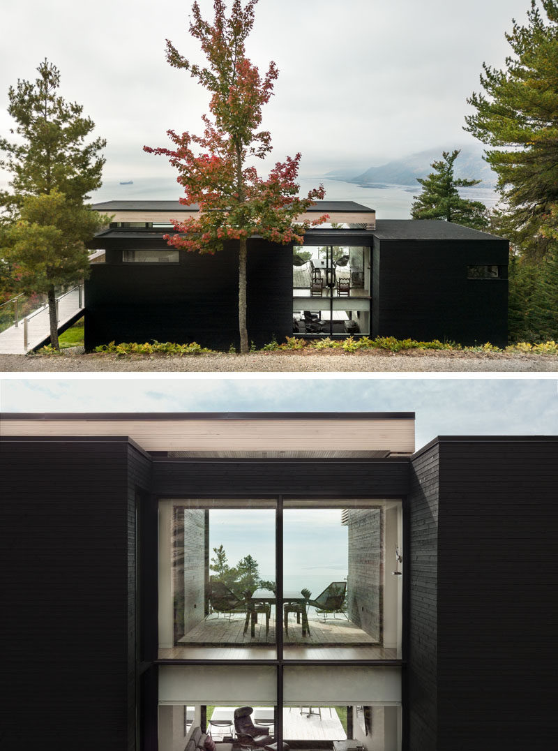 Upon arriving at this modern home, mature vegetation surrounds the house and the dark exterior of the home blends into the color of the bark of nearby trees. #ModernHouse #Architecture #Windows