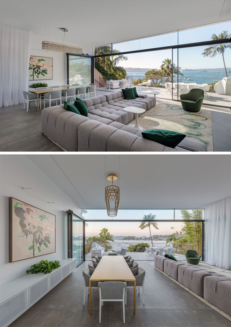 The social areas of this modern house take full advantage of the water view, with the dining room and living room opening up to a deck with additional living space. #ModernInterior #LivingRoom #Deck