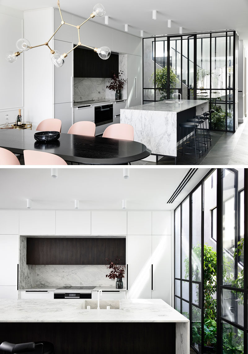 In this modern kitchen, floor-to-ceiling cabinetry against the wall frames the countertop and appliances, while the rangehood has been integrated into the counter to maximize storage and seamless surfaces. #ModernKitchen #KitchenDesign #Atrium