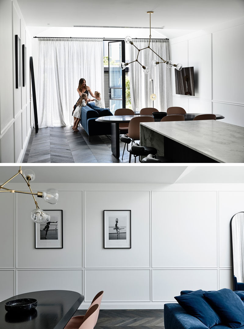 Chevron timber floors add some French allure to this modern interior and run throughout the open floor plan. Sheer curtains gently diffuse light, create privacy, and softly move in the breeze. #LivingRoom #PanelledWalls #InteriorDesign