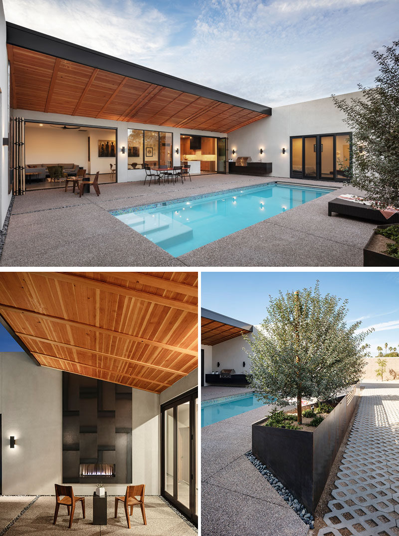 The rear private courtyard of this modern house revolves around a pool, while  a steel-clad outdoor fireplace is located on one side, and on the opposite side, there's a wall hung outdoor kitchen. #SwimmingPool #Courtyard #OutdoorFireplace #Planters