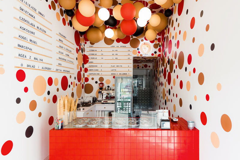 This modern ice-cream shop features colorful suspended balls and lighting from the ceilings, and dots on the walls complement the ball installation on the ceiling. #IceCreamShop #RetailDesign #InteriorDesign