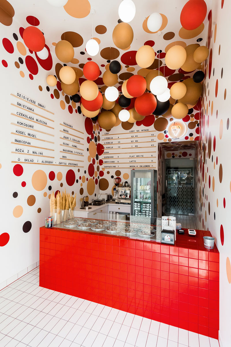 This modern ice-cream shop features colorful suspended balls and lighting from the ceilings, and dots on the walls complement the ball installation on the ceiling. #IceCreamShop #RetailDesign #InteriorDesign