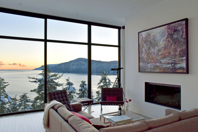 In this modern living room, there's a built-in fireplace for cold nights, and artwork adds a soft pop of color to the space. #Windows #LivingRoom