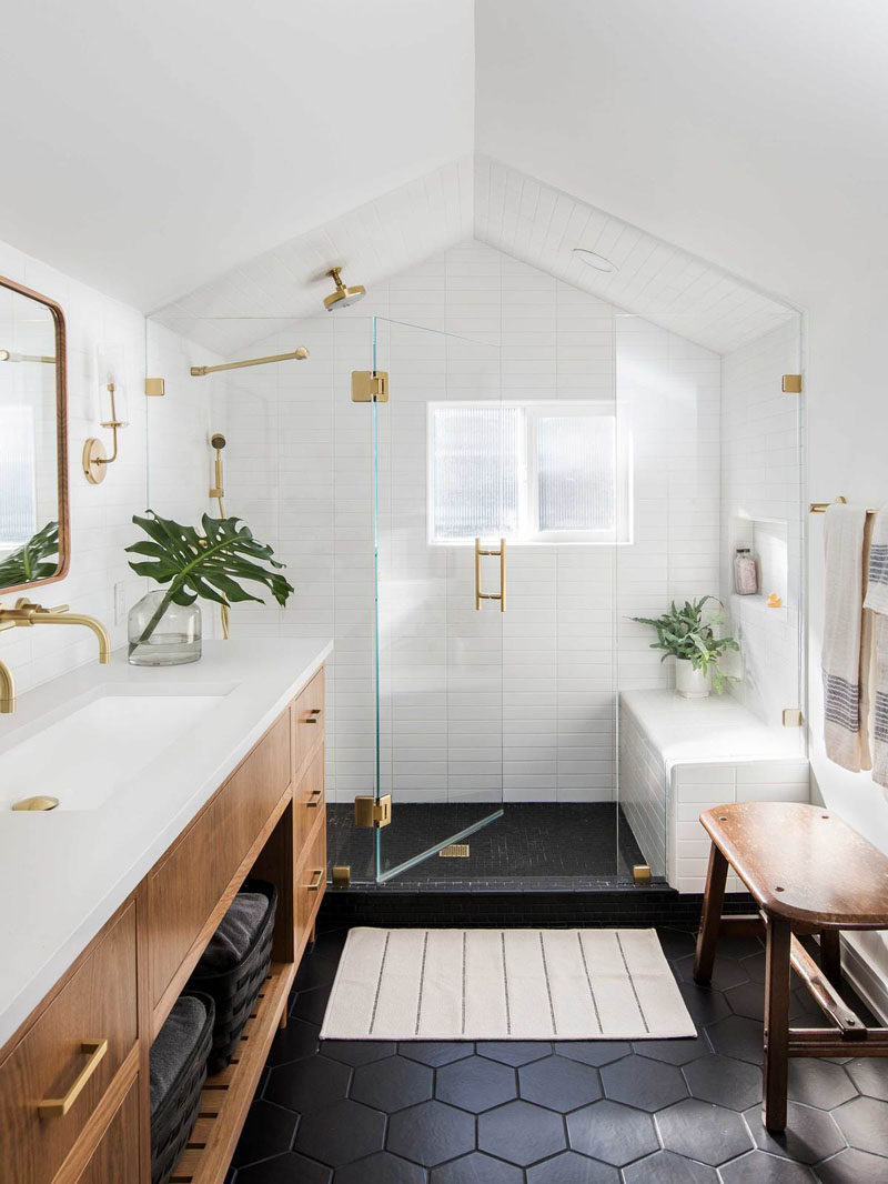 In this modern master bathroom, black hexagonal tiles cover the floor, while a glass shower screen separates the shower from the rest of the bathroom, and brass details add a luxurious touch. #MasterBathroom #ModernBathroom #BathroomDesign