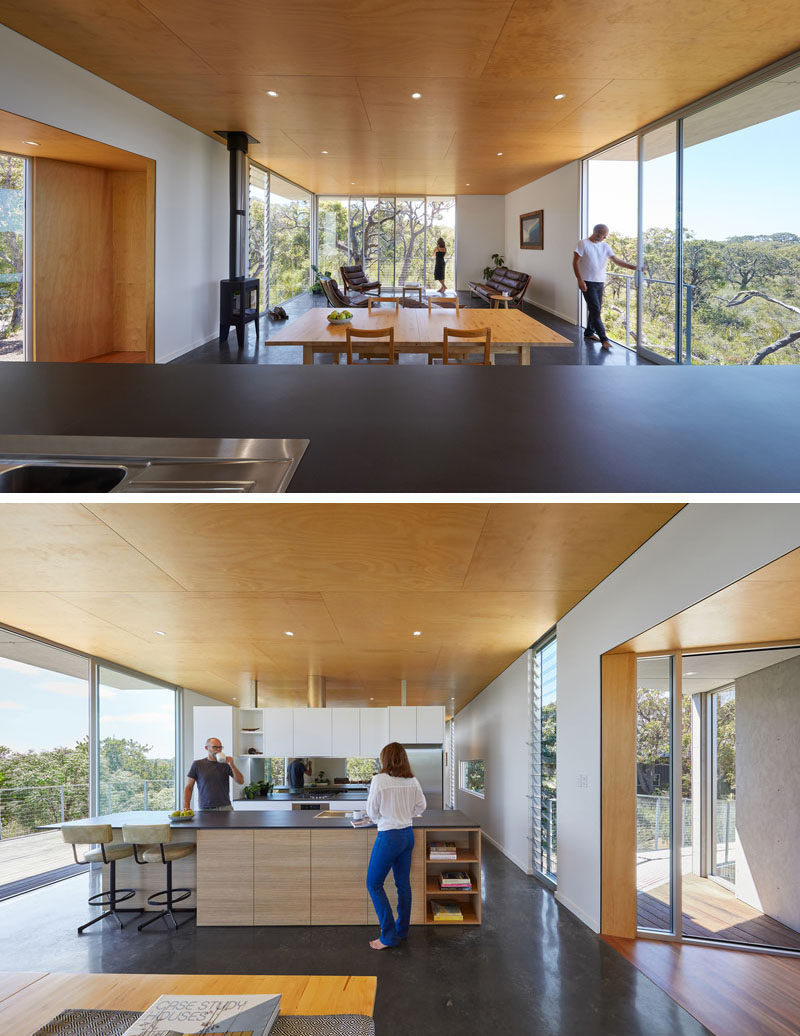 The open floor plan of this living space, dining area, and kitchen, allows the natural light from the floor-to-ceiling windows to filter throughout the home. #OpenFloorPlan #WoodCeiling #ModernKitchen