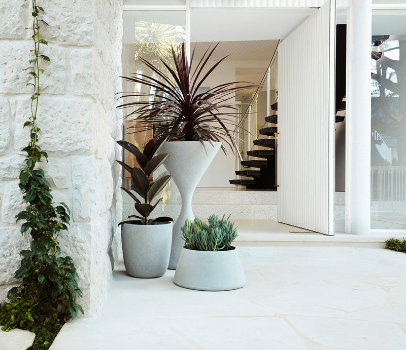 A large oversized, pivoting white front door welcomes visitors to this modern house. #FrontDoor #PivotingDoor