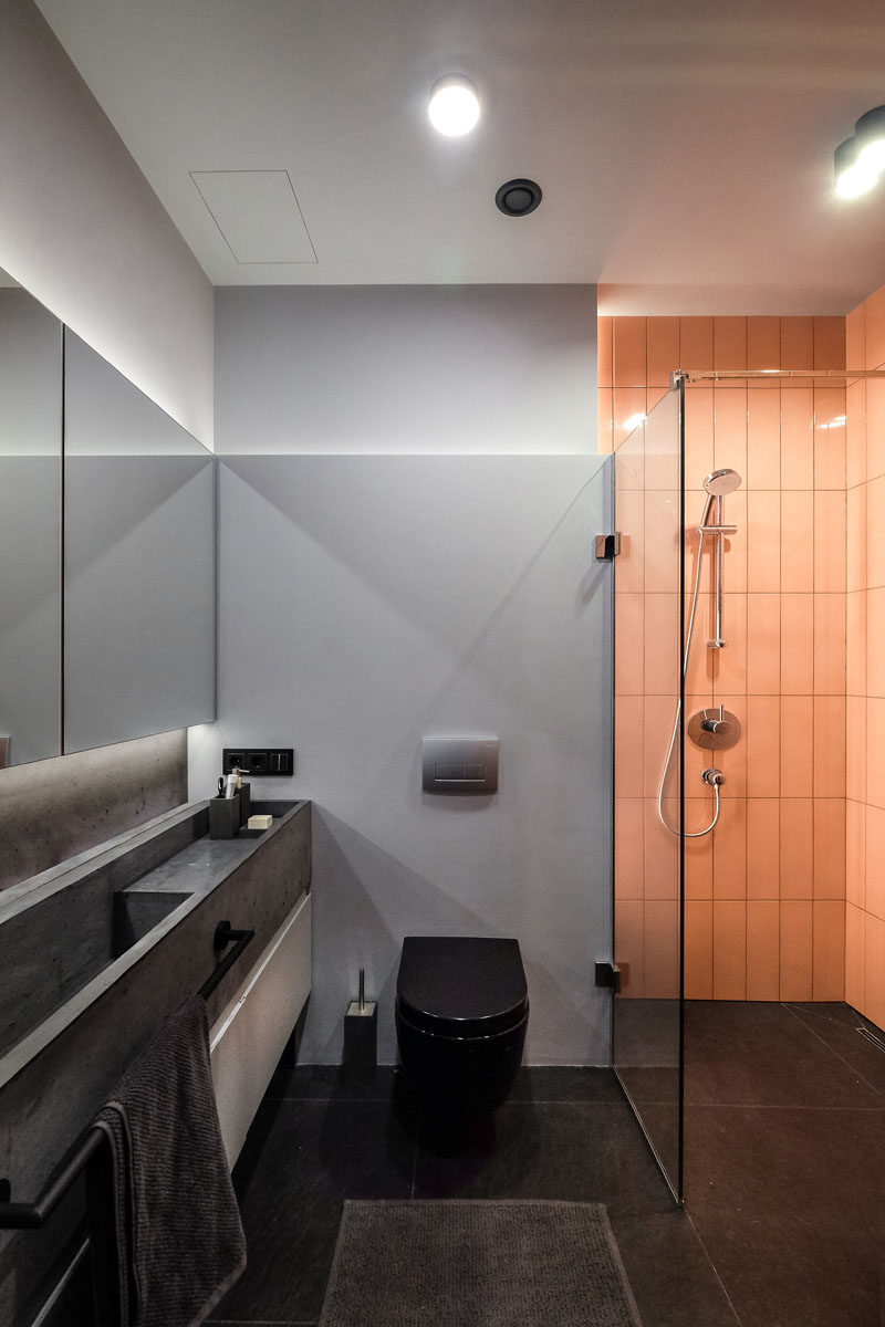 In this modern bathroom, the monochrome palette has been brightened up with the use of a peach subway tile in the shower. #ModernBathroom #BathroomDesign