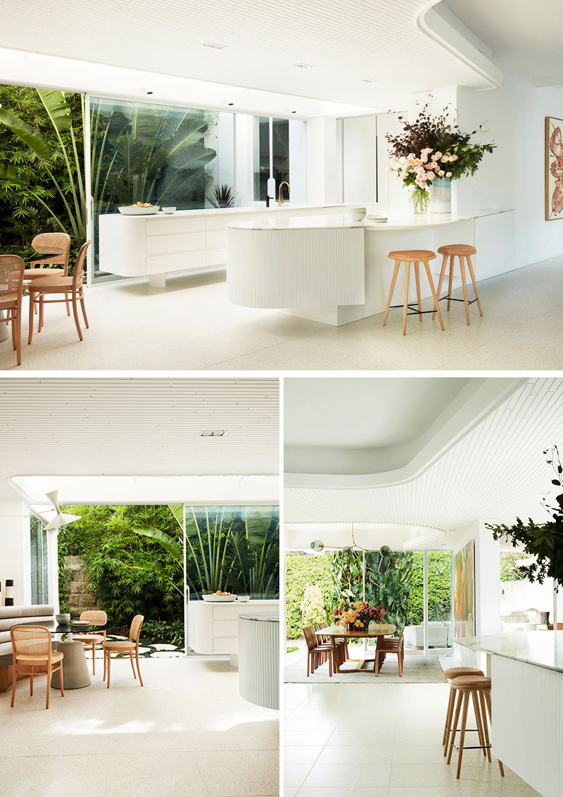 This modern white kitchen sits beside a small breakfast area and a larger dining area. #WhiteKitchen #InteriorDesign #ModernKitchen